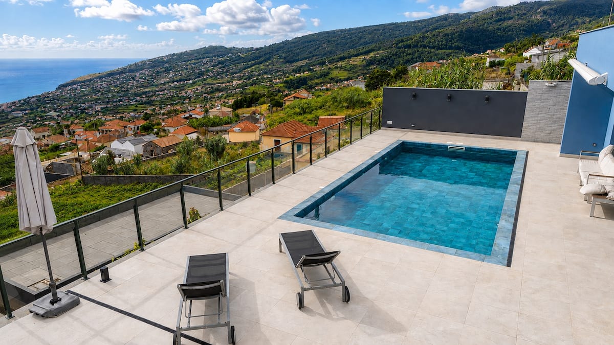Piscina e encosta verde sobre Arco da Calheta