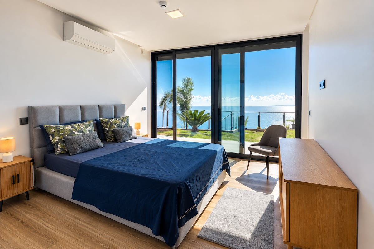 Quarto com cama queen size e porta de vidro para o terraço