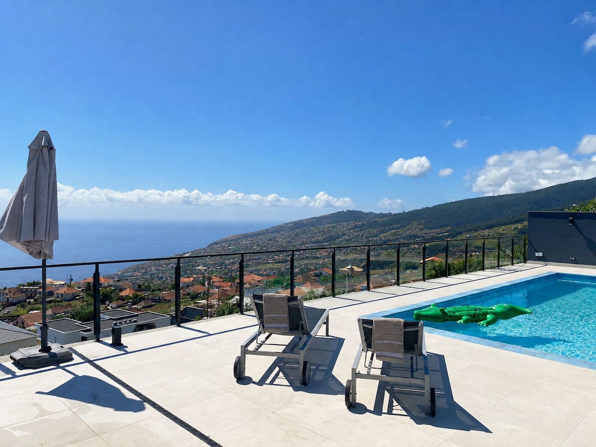 Terraço da piscina com espreguiçadeiras e vista de mar
